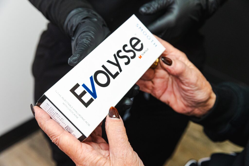 Close-up of a provider and patient holding a box of Evolysse, a brand of injectable filler.