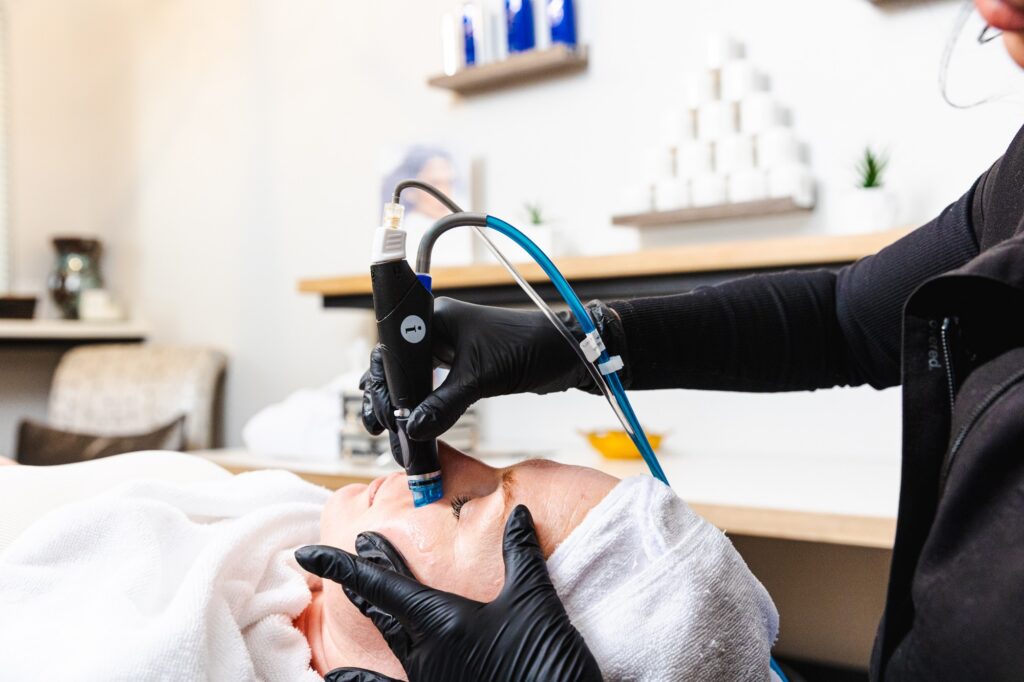 Close-up of a provider using the Hydrafacial handpiece on a patient's skin during her dermaplaning facial in Myrtle Beach.