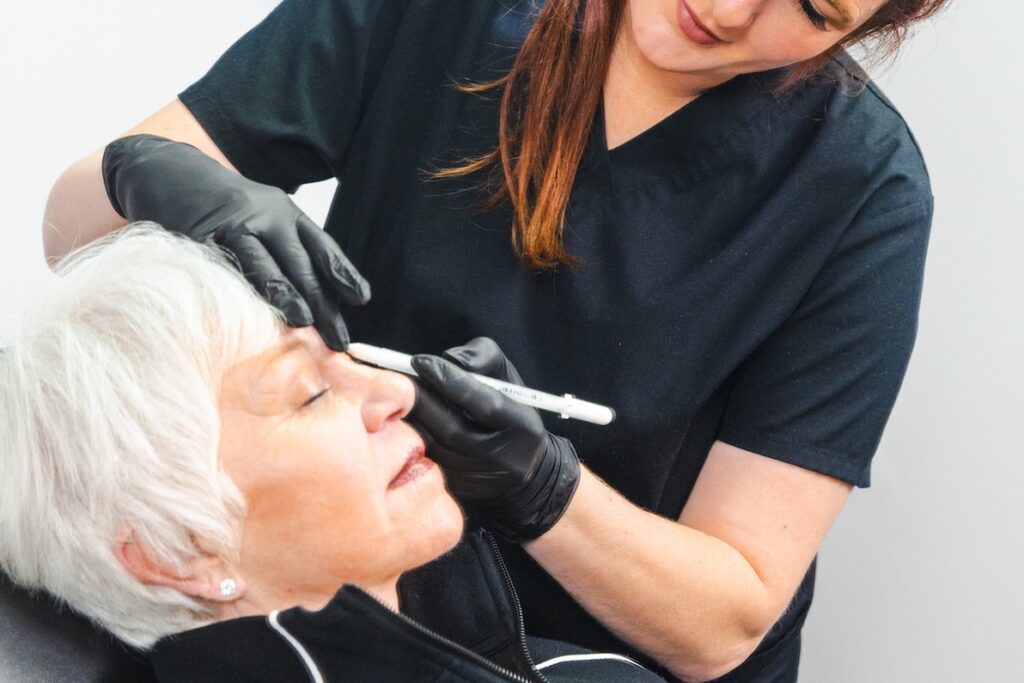 Close-up of a provider marking a patient's eyebrows with a pen before permanent cosmetic application in Myrtle Beach.